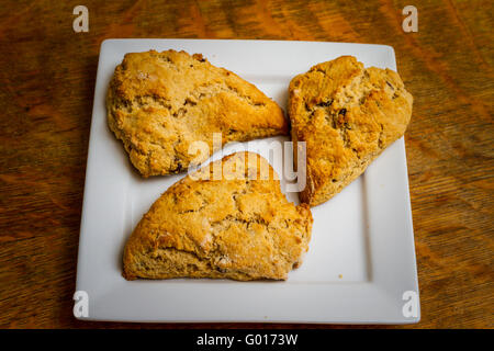 Scones aux raisins et cannelle sur une plaque carrée blanche Banque D'Images