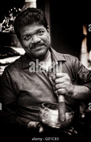 Image en noir et blanc d'un homme dans un magasin démontrant un Indien Bol chantant Banque D'Images