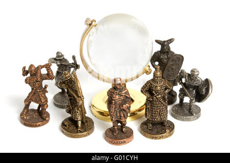 Figurines en métal des anciens guerriers autour de globe de verre isolé sur blanc. Concept de l'histoire militaire. Banque D'Images