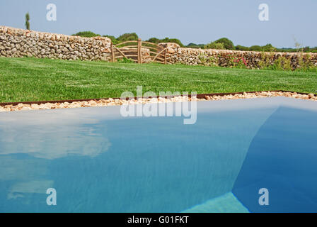Menorca, Minorque : une barrière en bois, pelouse, mur en pierre et le meinorcan n réflexions piscine campagne Banque D'Images