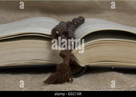 Bible ouverte noire et croix de bois sur toile rustique Banque D'Images