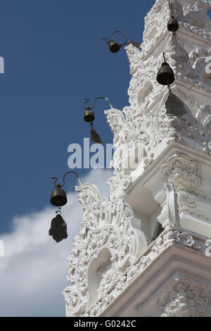 Wind-cloches sur un tour blanc sculpté dans un temple bouddhiste en Thaïlande Banque D'Images