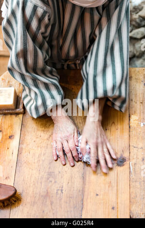 Détail de la mains d'une lavandière lave des vêtements sur une planche de bois. Banque D'Images