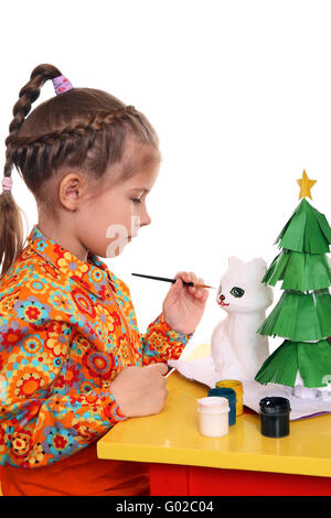 Une jeune fille peint la figure d'un chat blanc hors de papier-mâché. La préparation pour la nouvelle année Banque D'Images
