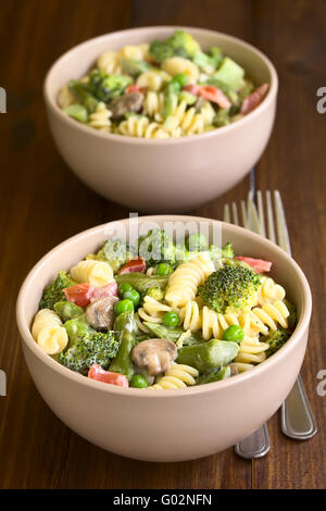 Pâtes Primavera aux asperges vertes, pois, brocolis, champignons et tomates à la crème servi dans deux bols Banque D'Images