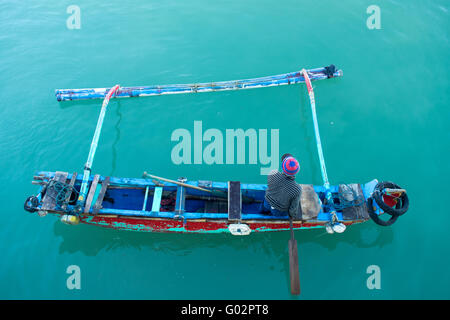 Un pêcheur dans une pagaie jukung traditionnel en bois ou en bateau de la Baie de Jimbaran, Bali. Banque D'Images