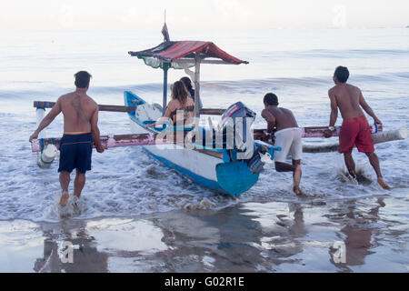 Les gens de lancer un bateau en bois dans la baie de Jimbaran, Bali. Banque D'Images