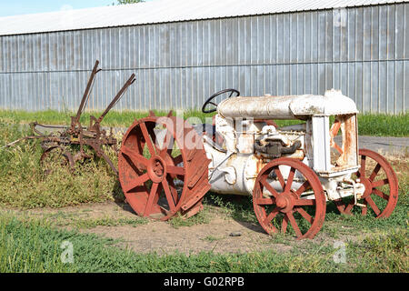 Old vintage rouille du tracteur à l'herbe pour illustrer le concept de l'abandon, à la retraite, à gauche à la rouille Banque D'Images