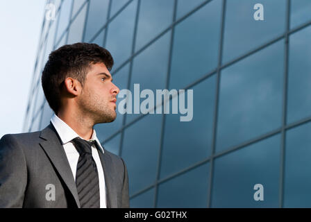 Jeune homme à la recherche de bons espoirs sur fond de construction moderne Banque D'Images