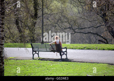 Athletic Girl aux cheveux rouges sur le banc du parc Kelvingrove, Glasgow en Ecosse Banque D'Images