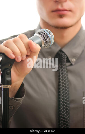 Businessman ou chanteur en manteau gris avec neck tie holding microphone à la main prêt à effectuer Banque D'Images