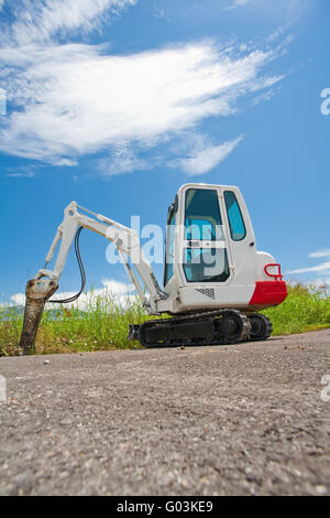 Petit tracteur Caterpillar se dresse sur l'asphalte contre le ciel bleu Banque D'Images