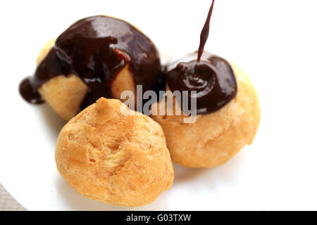 Verser la sauce au chocolat chaude sur profiteroles fraîches Banque D'Images