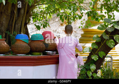 Moine birman frais fille de l'eau d'un pot en terre cuite au monastère bouddhiste de Rangoon, Rangoon Rangoon, Myanmar Banque D'Images