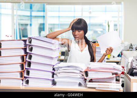 African American Woman choqué à la table avec de nombreux documents dans Office Banque D'Images