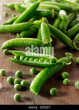 La nourriture reste la vie de petits pois et pois fraîchement cueillis dans le jardin dans les gousses sur une table rustique dans un être de cuisine préparé Banque D'Images