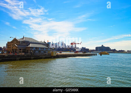 Hélicoptère à l'atterrissage à l'hélisurface dans Lower Manhattan, New York, USA, le East River. Pier 6. Gratte-ciel de Brooklyn sur l'arrière-plan. Les gens sur le quai. Banque D'Images