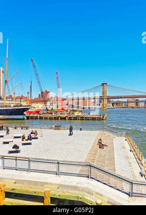 NEW YORK, USA - 25 avril 2015 : les touristes se détendre sur les chaises longues dans la jetée de Manhattan, New York. Vue depuis le Ferry Pier Banque D'Images