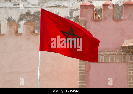 Vent agitant le drapeau marocain. Architecture traditionnelle dans l'arrière-plan. Banque D'Images