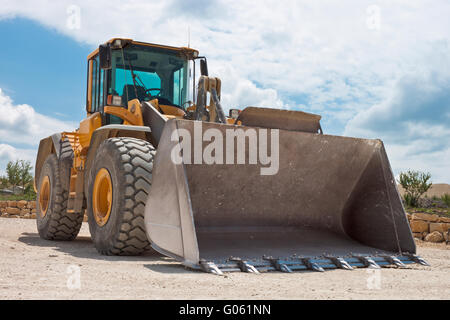 Excavatrice jaune sur un site de construction contre le ciel bleu Banque D'Images