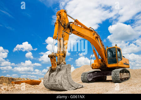 Excavatrice jaune sur un site de construction contre le ciel bleu Banque D'Images