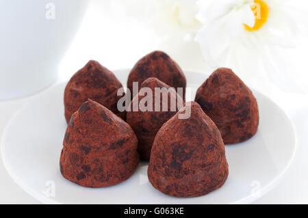 Truffes au chocolat sur une plaque blanche avec des fleurs Banque D'Images