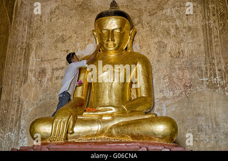 L'homme applique la feuille d'or à l'image de Bouddha, la Birmanie Banque D'Images