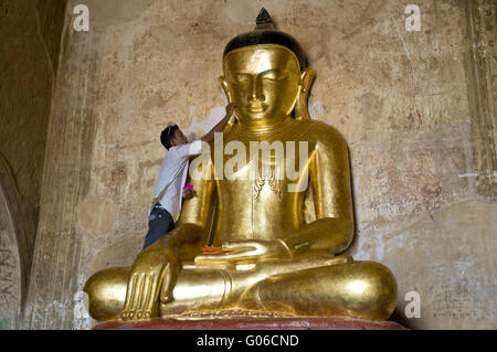 L'homme applique la feuille d'or à l'image de Bouddha, la Birmanie Banque D'Images