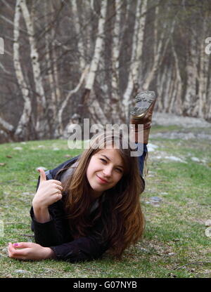 Belle jeune fille couchée sur l'herbe et montre Banque D'Images