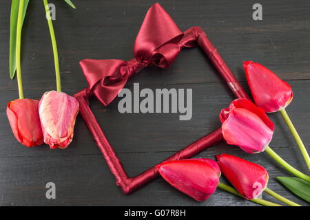 Tulipes rouges et un cadre photo décoré sur une table en bois foncé Banque D'Images