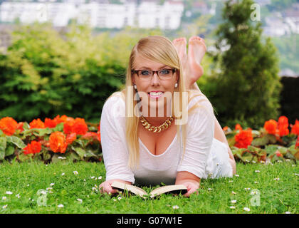 Jeune femme est couché sur les herbages et de la lecture Banque D'Images