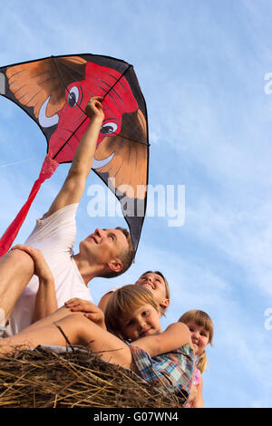 Famille de quatre personnes contre le ciel bleu flying kite. Banque D'Images