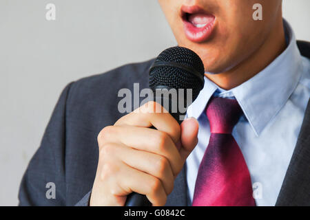 Les jeunes parler man holding microphone sans confiance isolées sur fond blanc Banque D'Images
