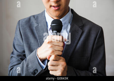 Les jeunes parler man holding microphone sans confiance isolées sur fond blanc Banque D'Images