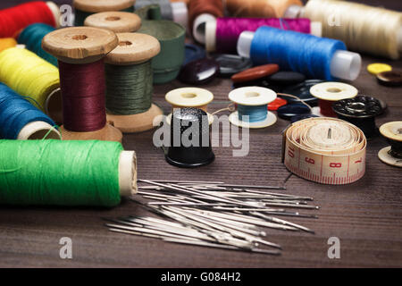 Boutons d'aiguilles et les threads sur table en bois brun Banque D'Images