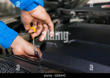 Contrôle mécanique de la voiture le niveau d'huile dans une voiture garage service Banque D'Images