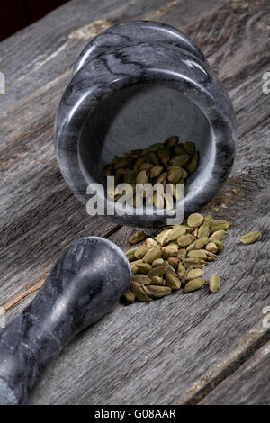 De cardamome au mortier sur une vieille table de cuisine Banque D'Images