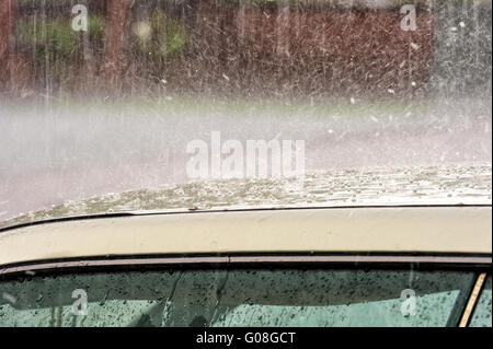 La pluie et la grêle qui tombe sur un toit de voiture Banque D'Images