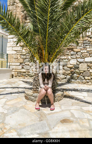 Triste fille assise sur le fond d'un palmier Banque D'Images