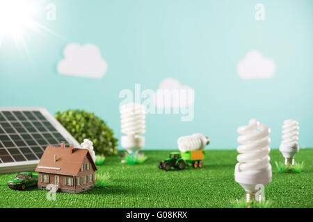 Environmental Friendly toy town avec modèle maison, lampes CFL que des arbres et un tracteur transportant une ampoule Banque D'Images
