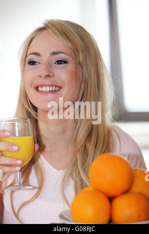 Femme buvant un verre de jus d'orange frais Banque D'Images