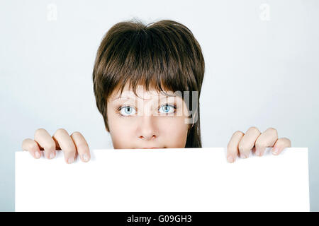 Face belle jeune femme se cacher derrière une grande bannière blanche Banque D'Images