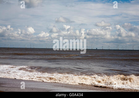 Les vagues se briser contre la plage avec le parc éolien dans l'arrière-plan Skegness Lincolnshire en Angleterre Banque D'Images