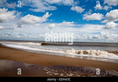 Les vagues se briser contre la plage avec le parc éolien dans l'arrière-plan Skegness Lincolnshire en Angleterre Banque D'Images