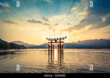 Le soleil se couche derrière le Torii flottant au sanctuaire d'Itsukushima sur Miyajima Banque D'Images