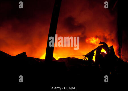 Silhouette de pompiers la lutte contre un feu faisant rage avec d'immenses flammes Banque D'Images