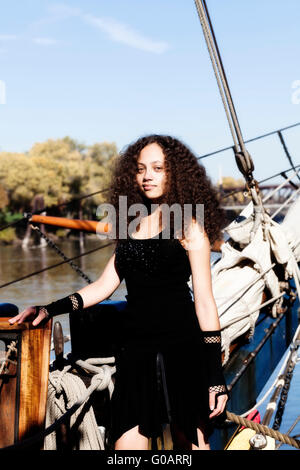 African American Woman in Black Dress Standing In Bow Sailing Ship Banque D'Images