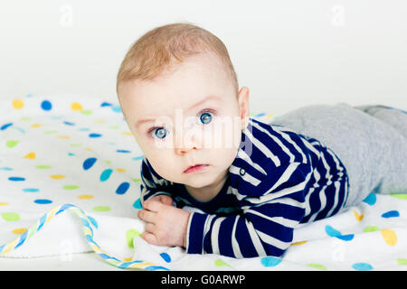 Mignon bébé dans des vêtements à rayures couchée sur une couverture Banque D'Images