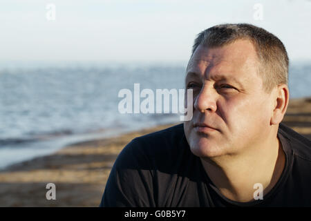 Bel homme d'âge moyen de penser à la plage Banque D'Images