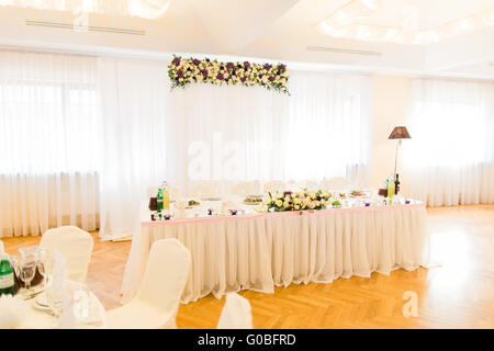 Élégamment décorées avec des fleurs blanches, des verres et des bougies de mariage pour célébrer restaurant Banque D'Images